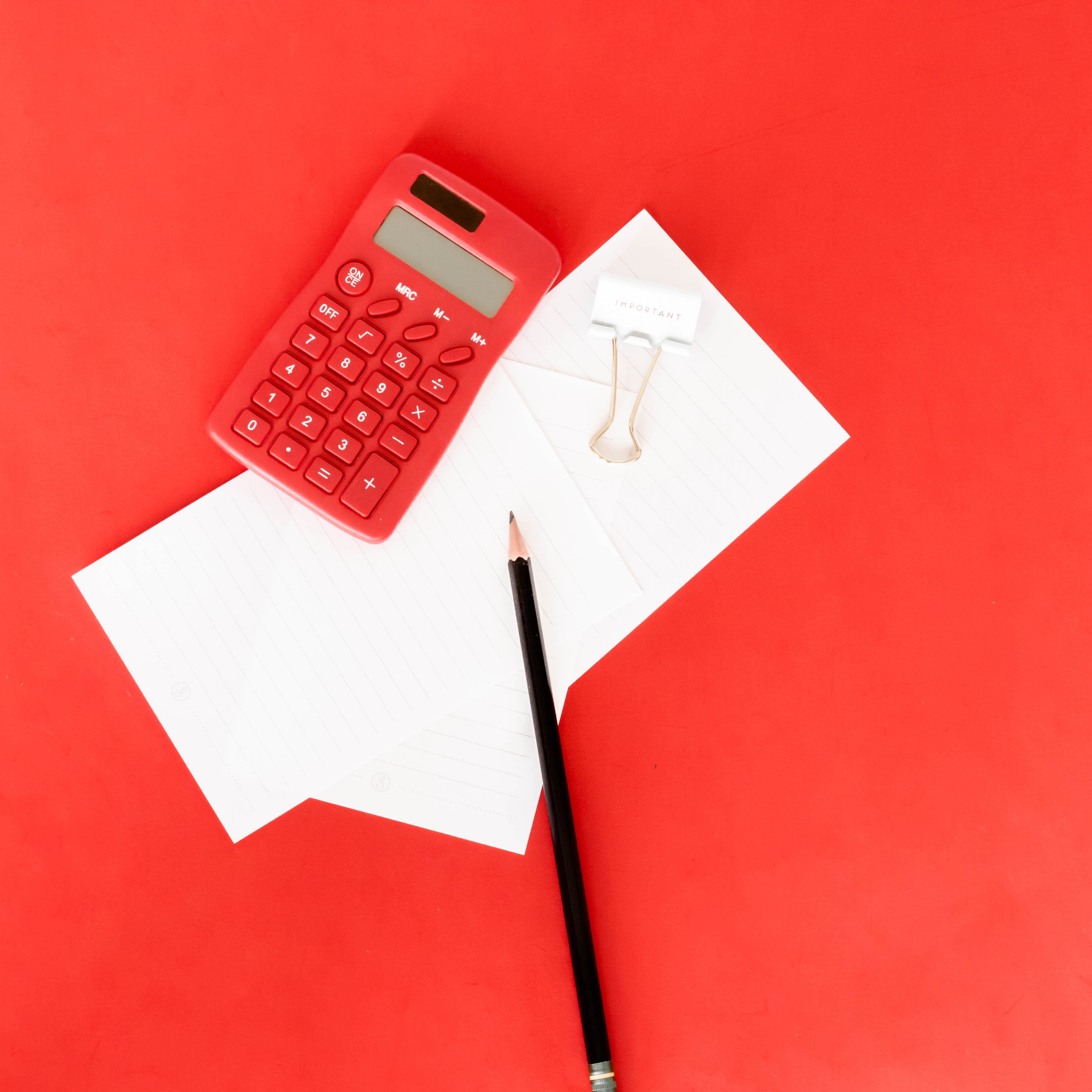 Red desk with pen, paper, and calculator
