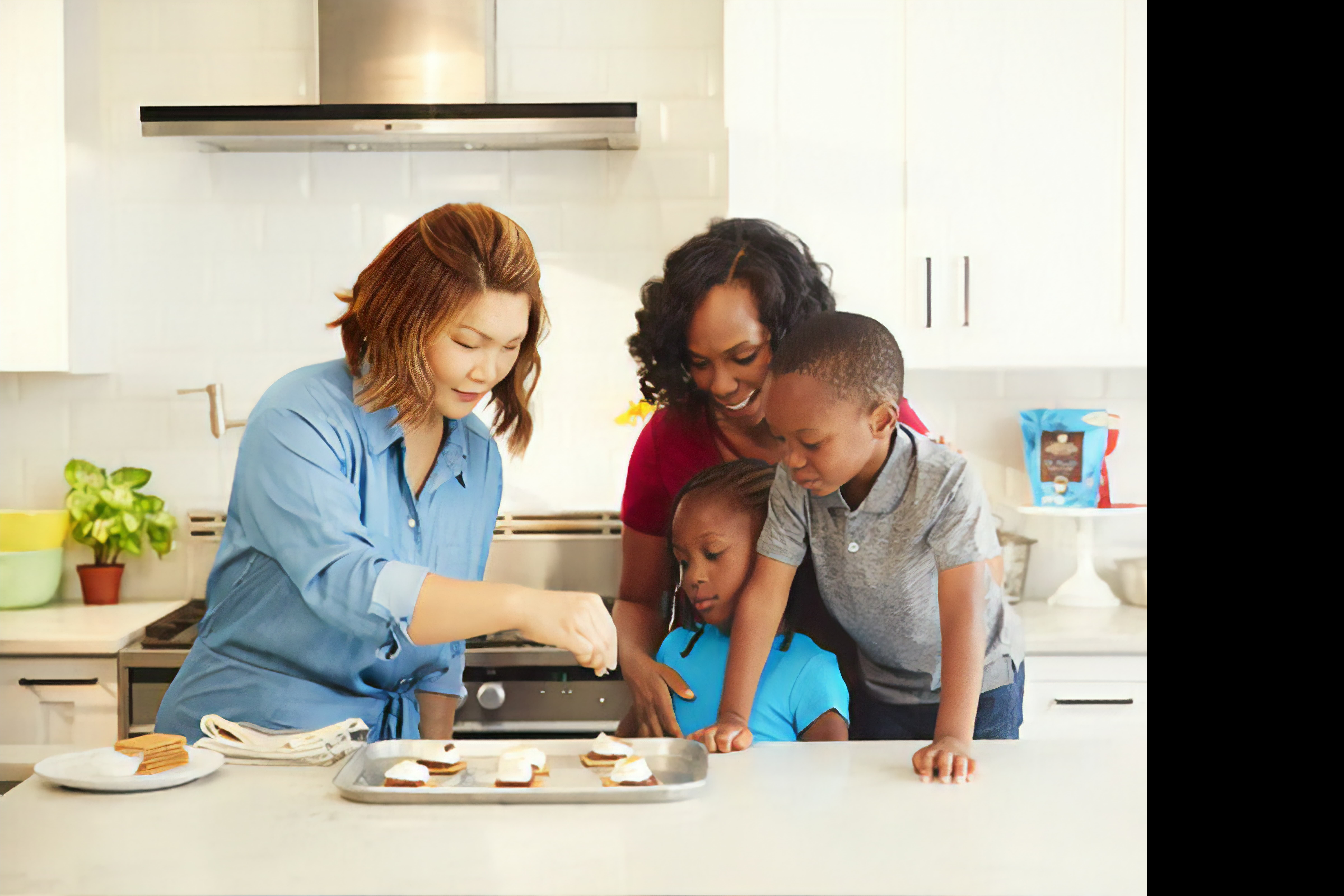 Black woman and two black children watching an Asian woman decorating a choclate dessert