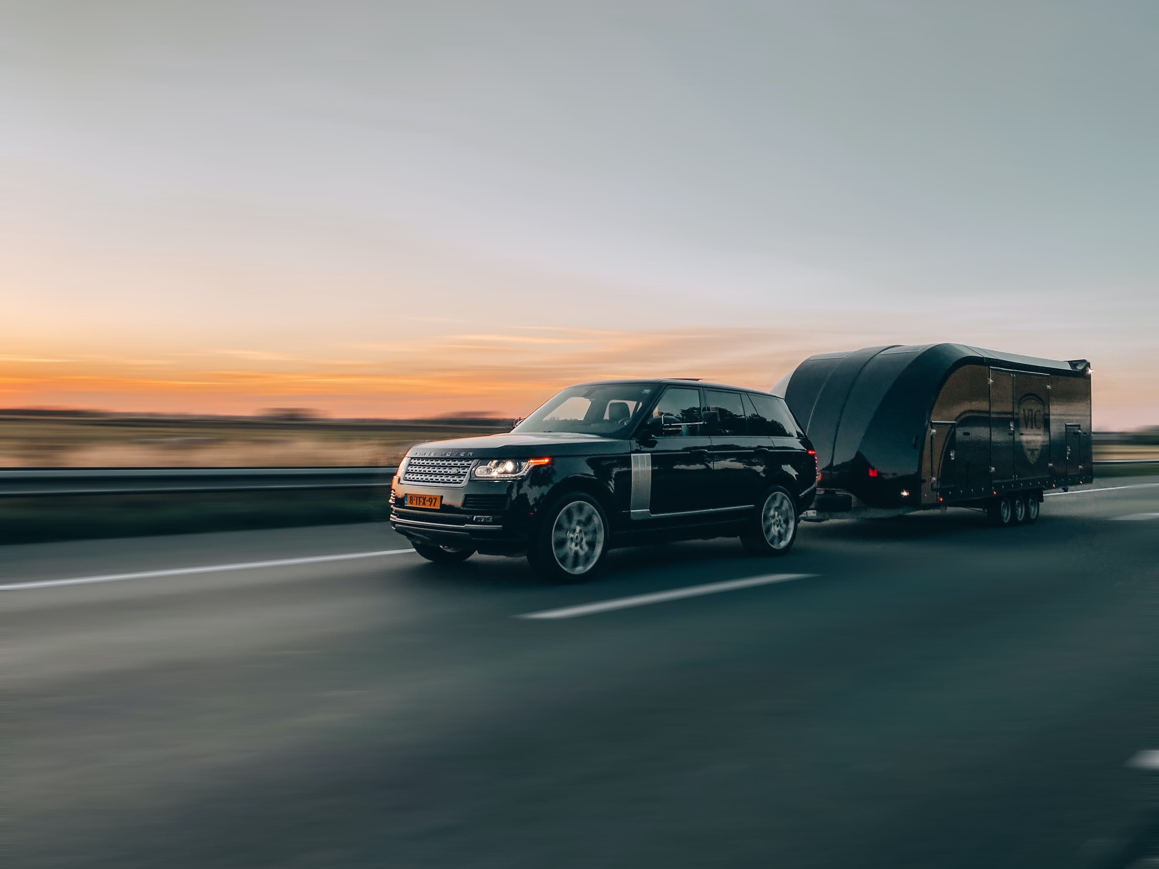 Car with a utility trailer driving down the road